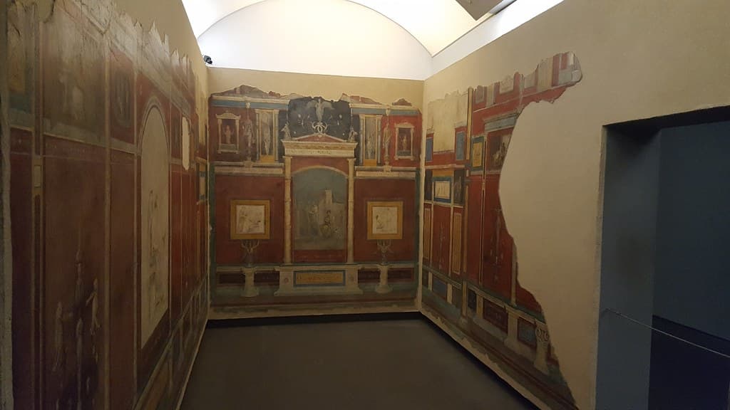 A small art gallery interior with paintings hung on white walls