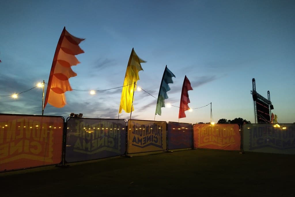 An outdoor evening film screening with colorful flags