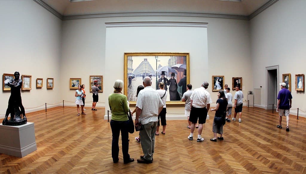 Visitors viewing framed paintings in a museum gallery